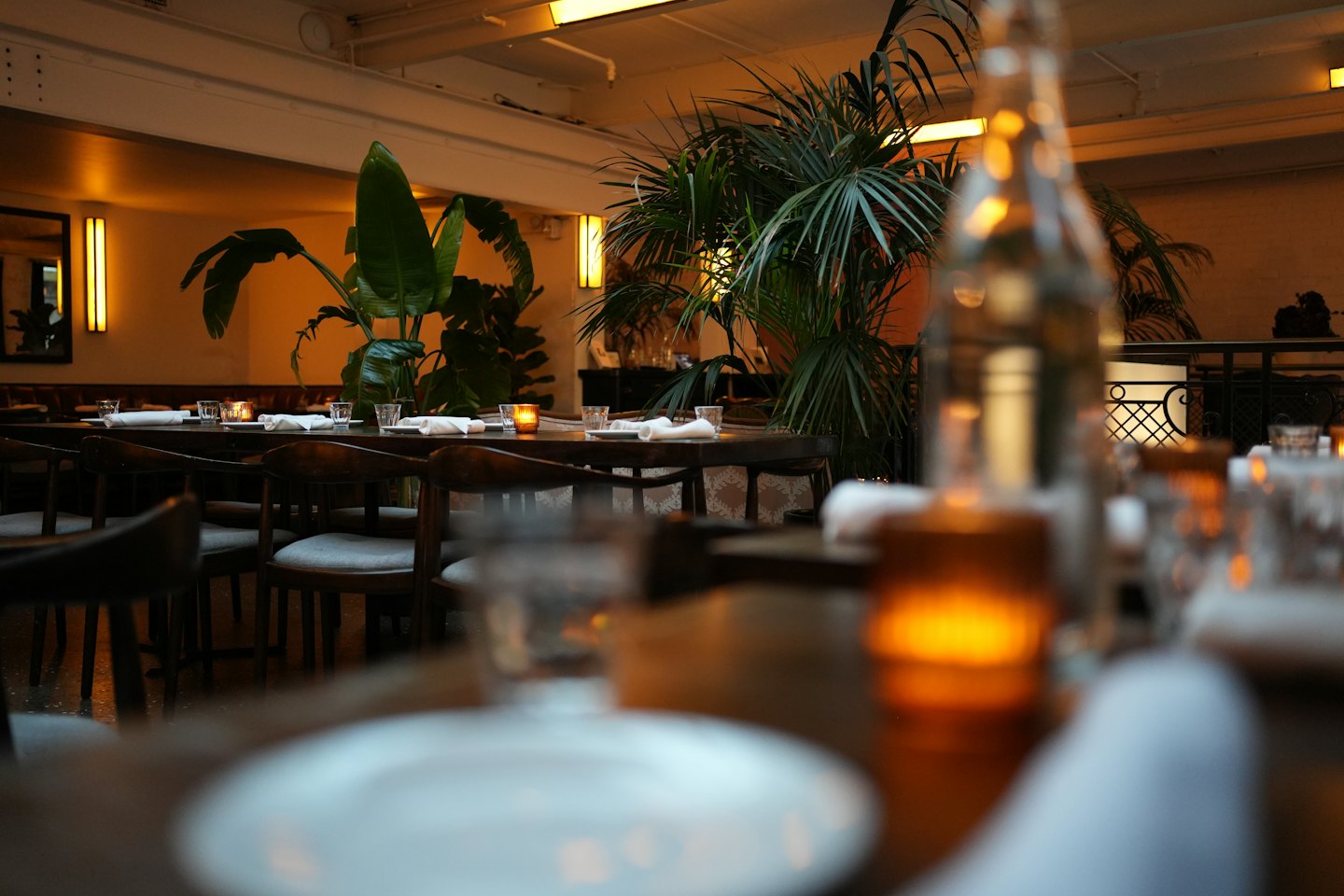 Mesas de madera con servicio y velas en un restaurante acogedor.