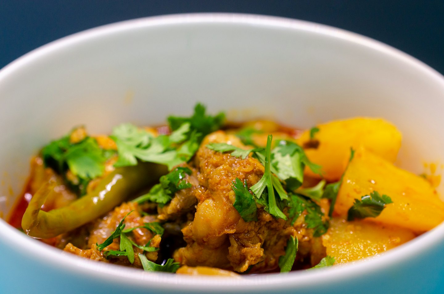 Curry de pollo y patatas sabroso servido en un cuenco blanco.