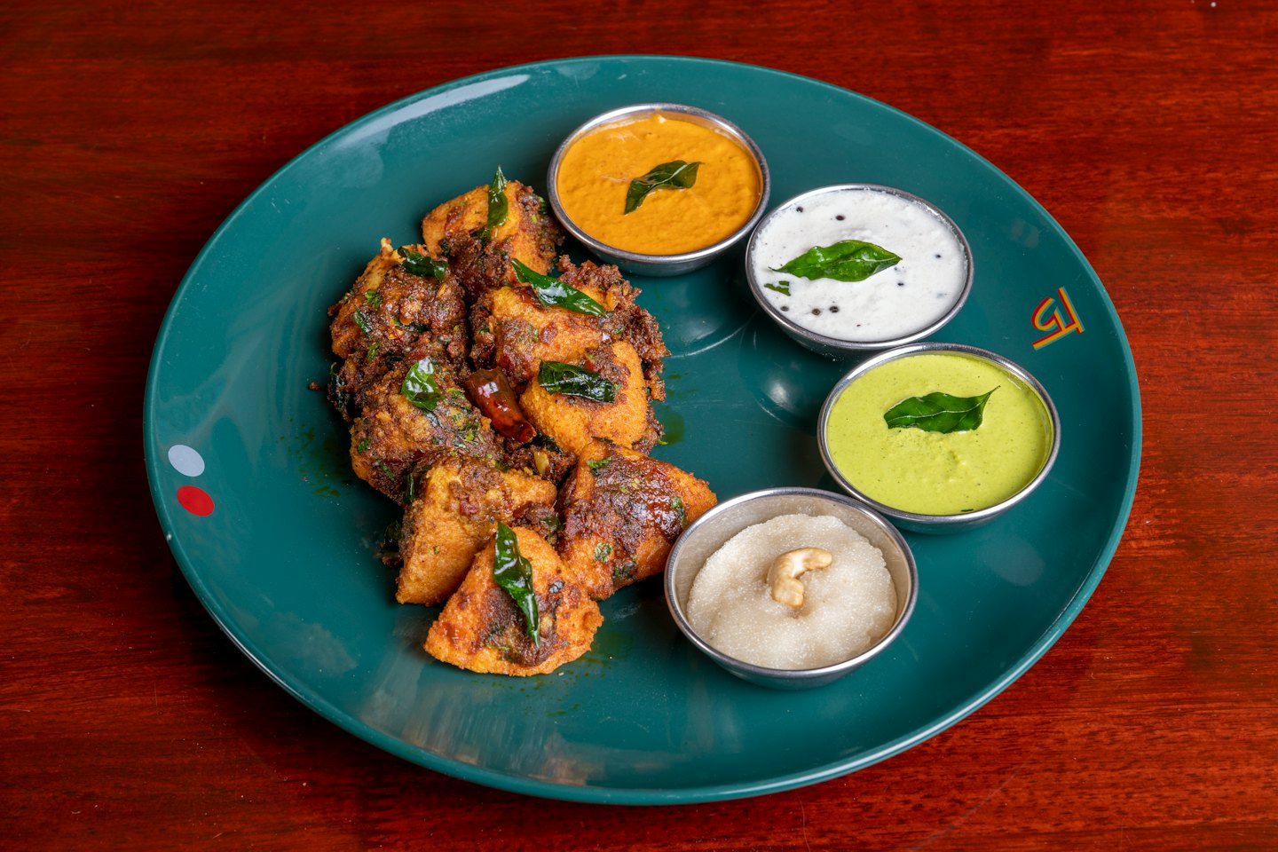 Plato frito del sur de la India con chutneys servido en un plato.