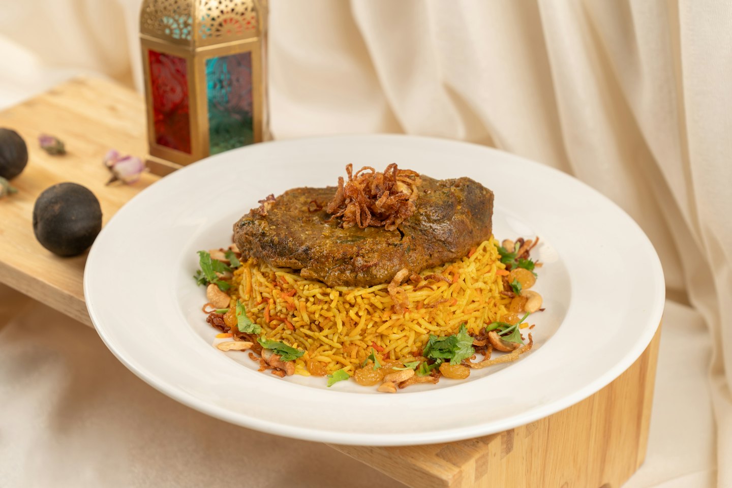 Carne sazonada servida sobre arroz amarillo con anacardos y cilantro.