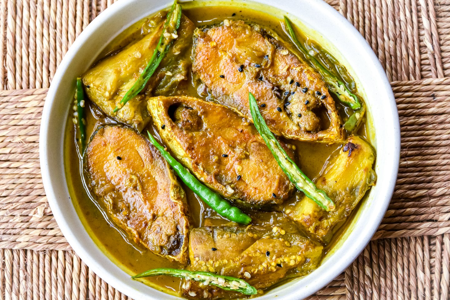 Curry de pescado con chile y berenjena en un cuenco blanco.