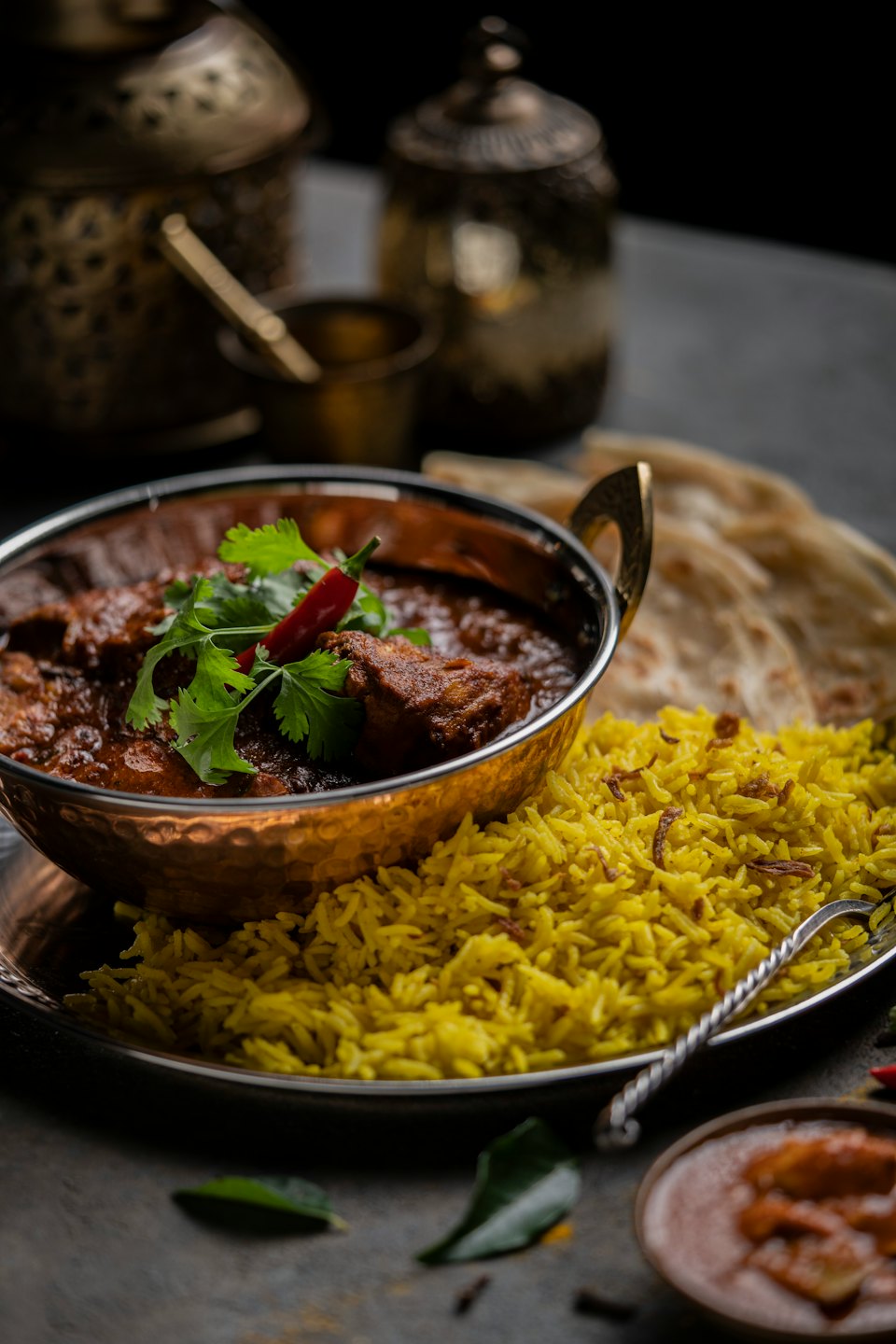 Curry de pollo indio con arroz pilaf y panes planos en un cuenco de cobre.
